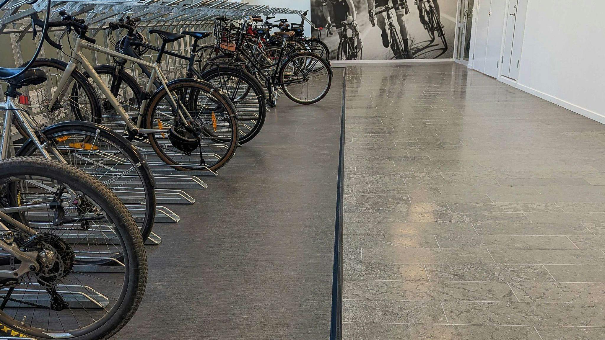 The Liquid Swords bicycle garage. Bikes lined up on the left side of the room on gray flooring.